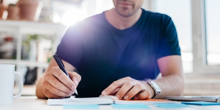 A man sitting at his desk writing out a budget.