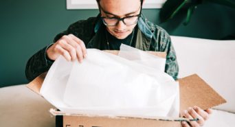 A man opening a cardboard box in his home.