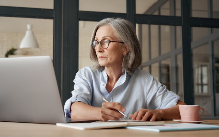 Frau an Laptop macht sich Notizen zur DSGVO für ihren Onlineshop