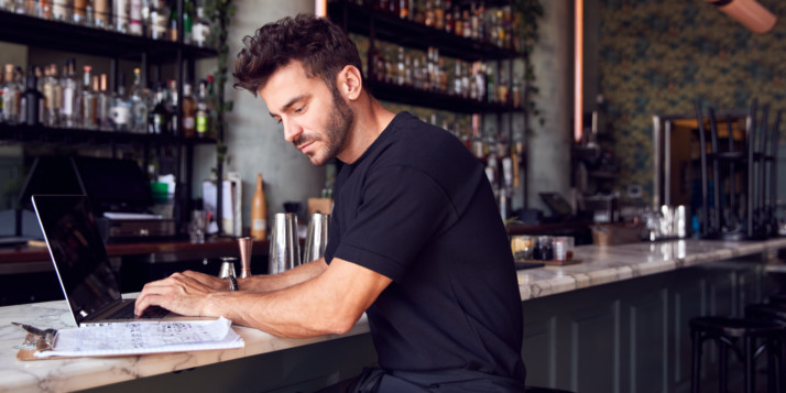 Ein junger Gastronom steht an der Theke seines Restaurants und überlegt sich Marketingstrategien