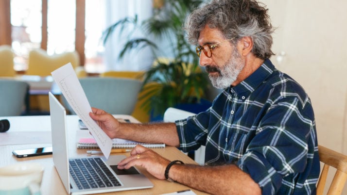 Ein Selbstständiger sitzt an seinem PC und arbeitet an seinen Mahnung-Vorlagen