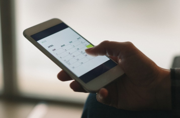 Eine Person checkt die Kalender App auf ihrem Smartphone.