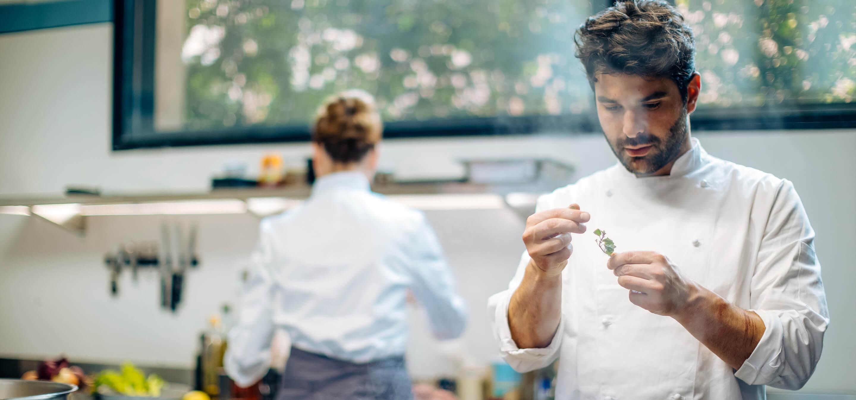 Dos chefs en una cocina profesional conversando sobre la página web de su restaurante