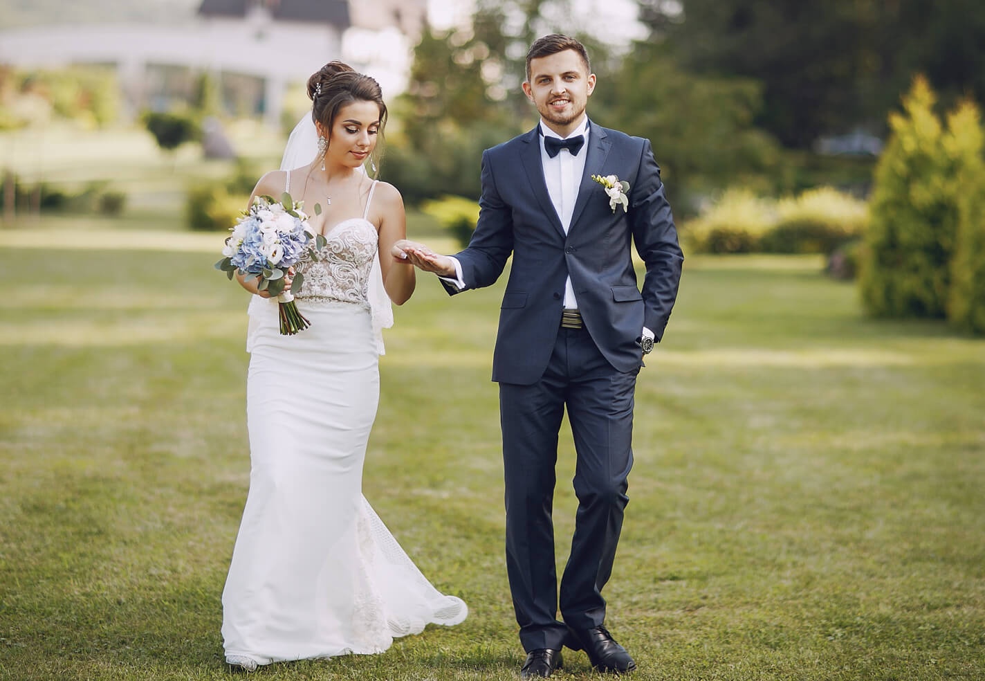 Una novia y un novio caminan de la mano el día de su boda.