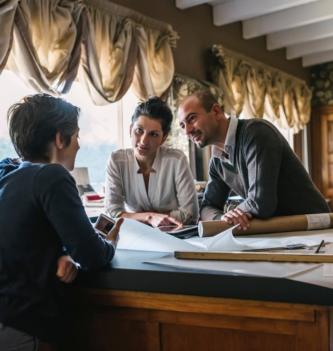 Three people review blueprint plans for their architecture website